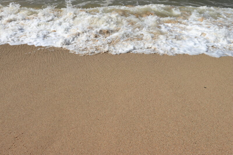 Ocean shore with sandy beach and advancing wave